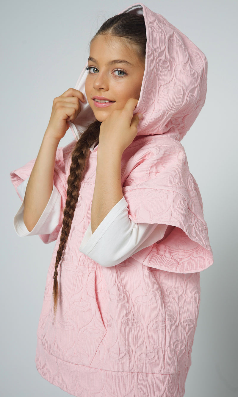 A young girl models a soft pink textured hoodie from Flowers and Ruffles, combining cozy comfort with elegant design details.