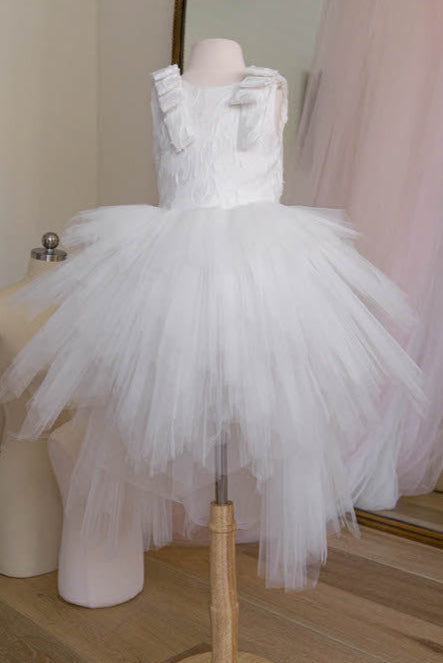 White tulle flower girl dress with layered skirt and bow shoulder details displayed on mannequin